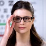 female in new eyeglasses looking at camera in optical store