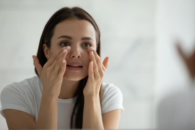 young woman wearing white t-shirt doing facial massage