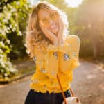 stylish smiling woman in yellow blouse wearing sunglasses, colorful summer fashion trend