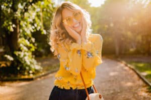 stylish smiling woman in yellow blouse wearing sunglasses, colorful summer fashion trend