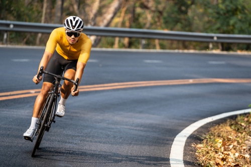 man in yellow cycling jersey riding on road bike with willful face.