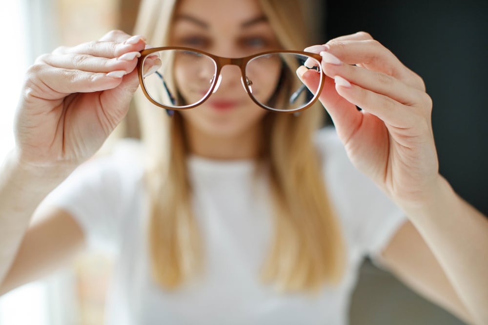 A woman holding her glasses away from her face