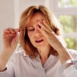 A woman with diabetes and glaucoma taking off her glasses and rubbing her eyes