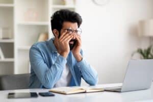 A man experiencing flashes and floaters rubbing his eyes