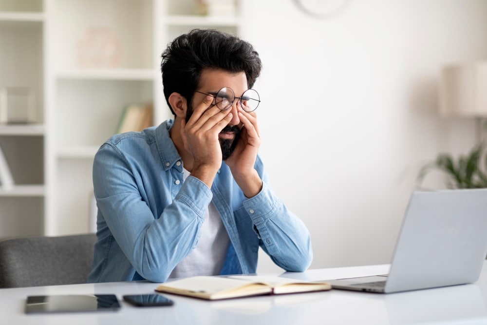 A man experiencing flashes and floaters rubbing his eyes