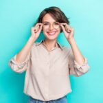 A woman smiling and putting on glasses