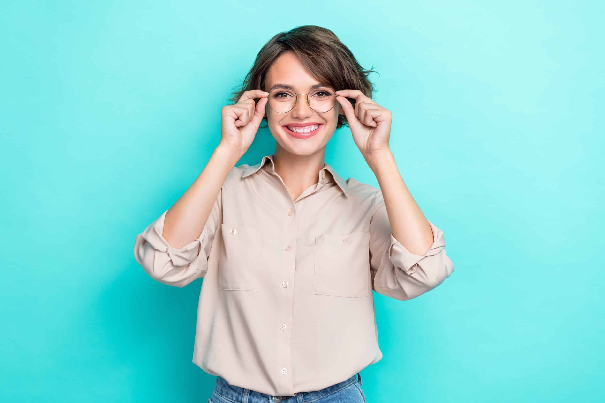 A woman smiling and putting on glasses