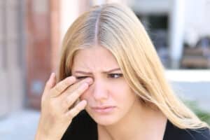 A woman with allergic eyelid problems rubbing her eye