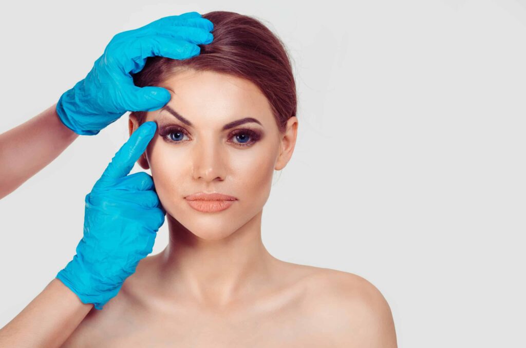 A doctor lifting a woman's brow before eyebrow surgery in Modesto, CA