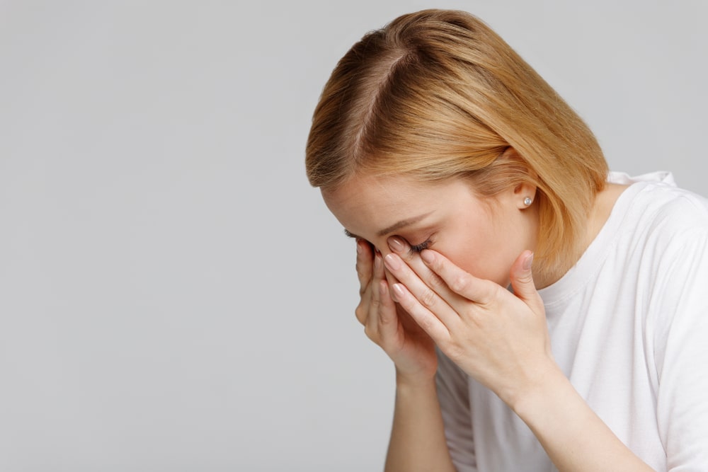 A woman with blurry vision rubbing her eyes