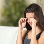 A woman with ectropion and skin disorders rubbing her eyes