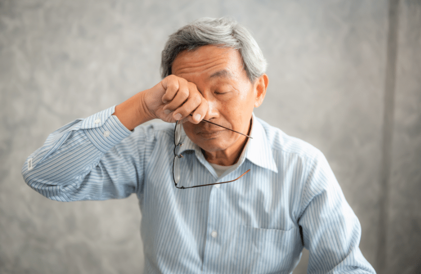 A man with uveitis rubbing his eyes