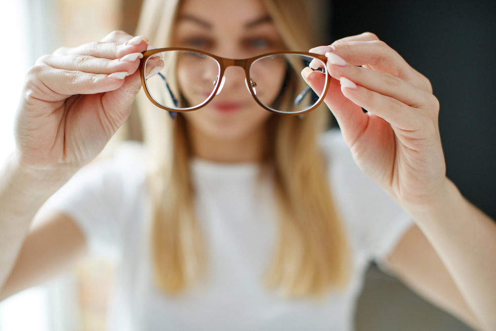 A woman looking at her glasses in Stockton, CA