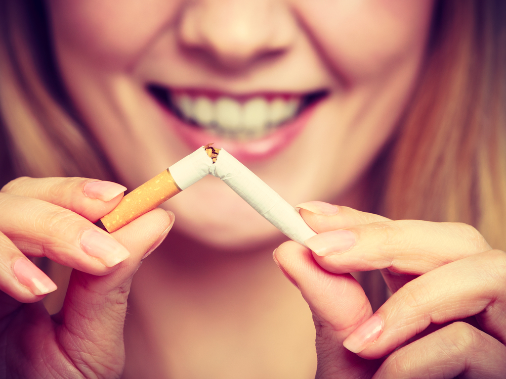 A close-up shot of a woman smiling and breaking a cigarette