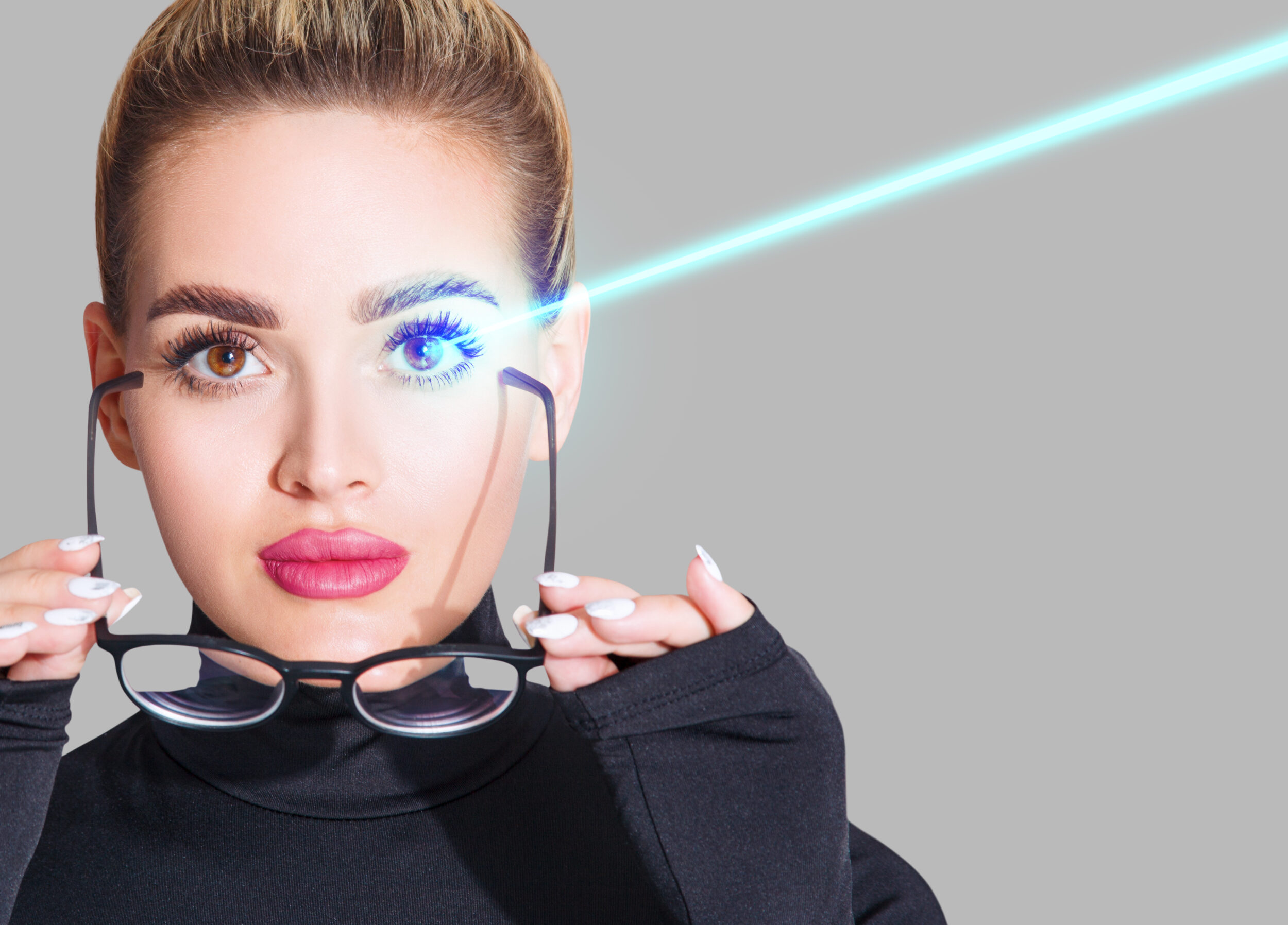 A woman holding a pair of glasses while being hit with a beam of blue light