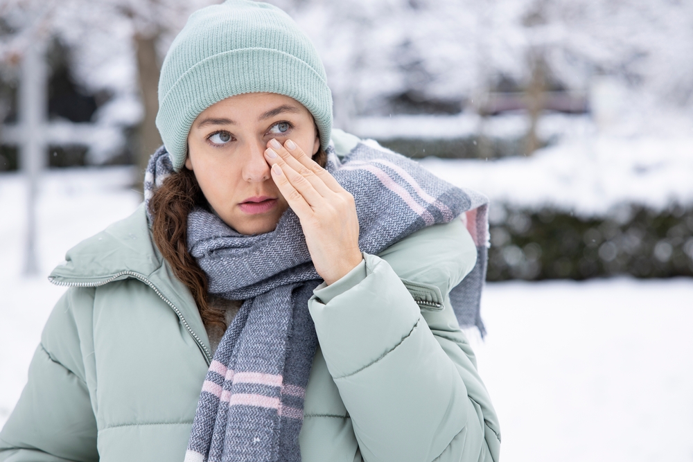 Woman suffering from persistent dry eye symptoms while standing outside during the snowy winter.